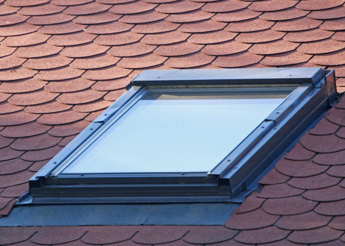 Fenêtre de toit type Velux installée sur une toiture en tuiles, avec raccords d’étanchéité pour une pose sécurisée.
